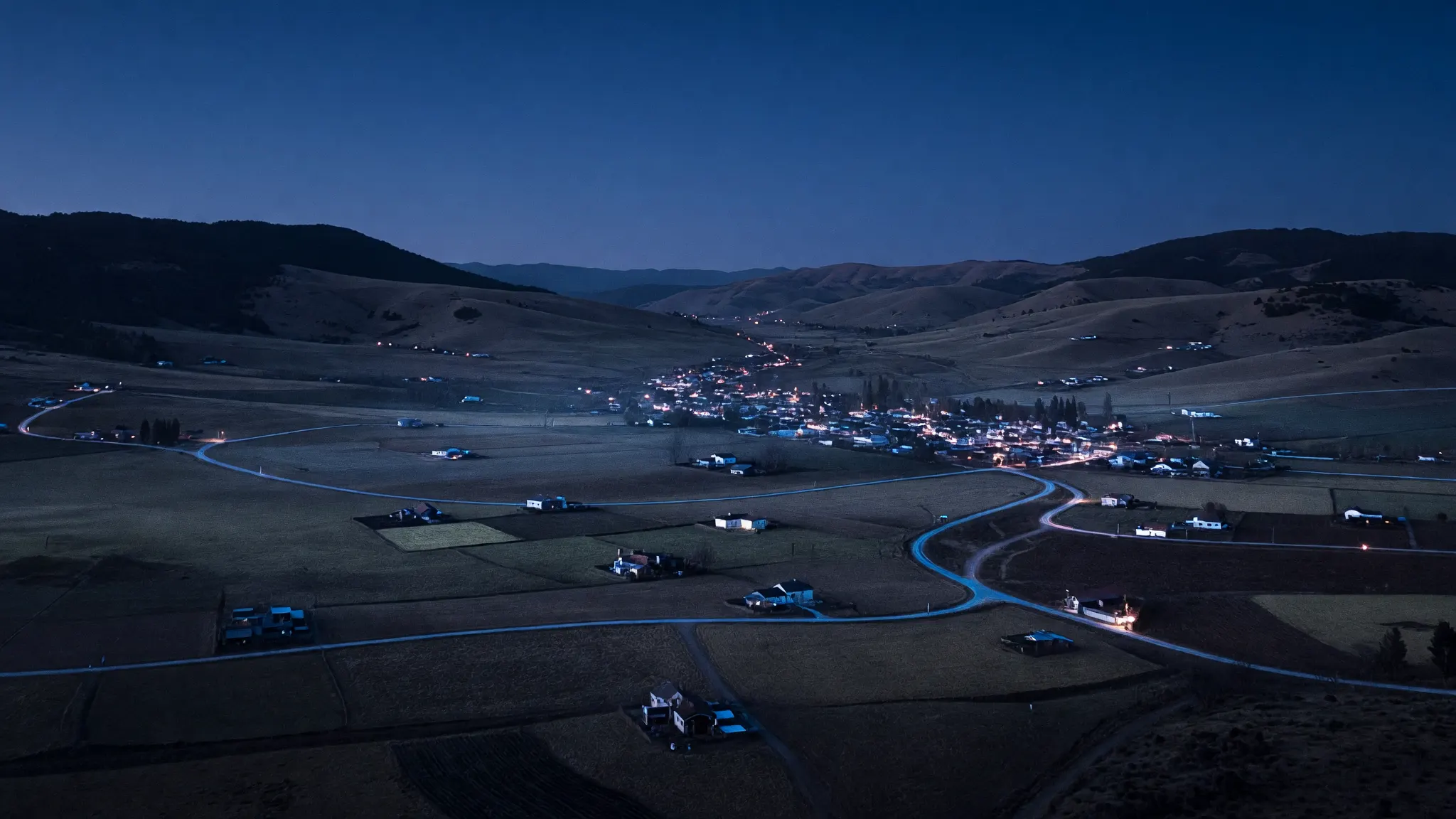 Vista aérea nocturna de un valle rural de la zona central con casas iluminadas